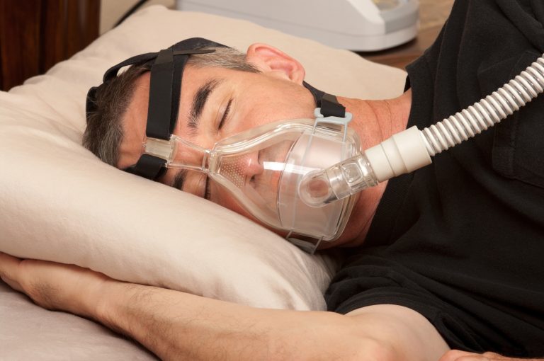 Hombre durmiendo con mascarilla de CPAP para tratar la apnea del sueño